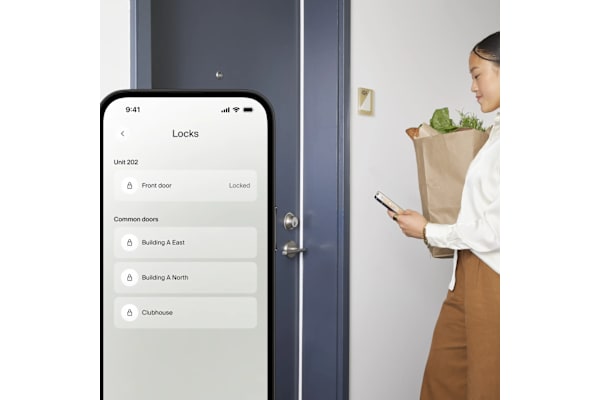 A woman is looking at her phone while standing in front of a door.